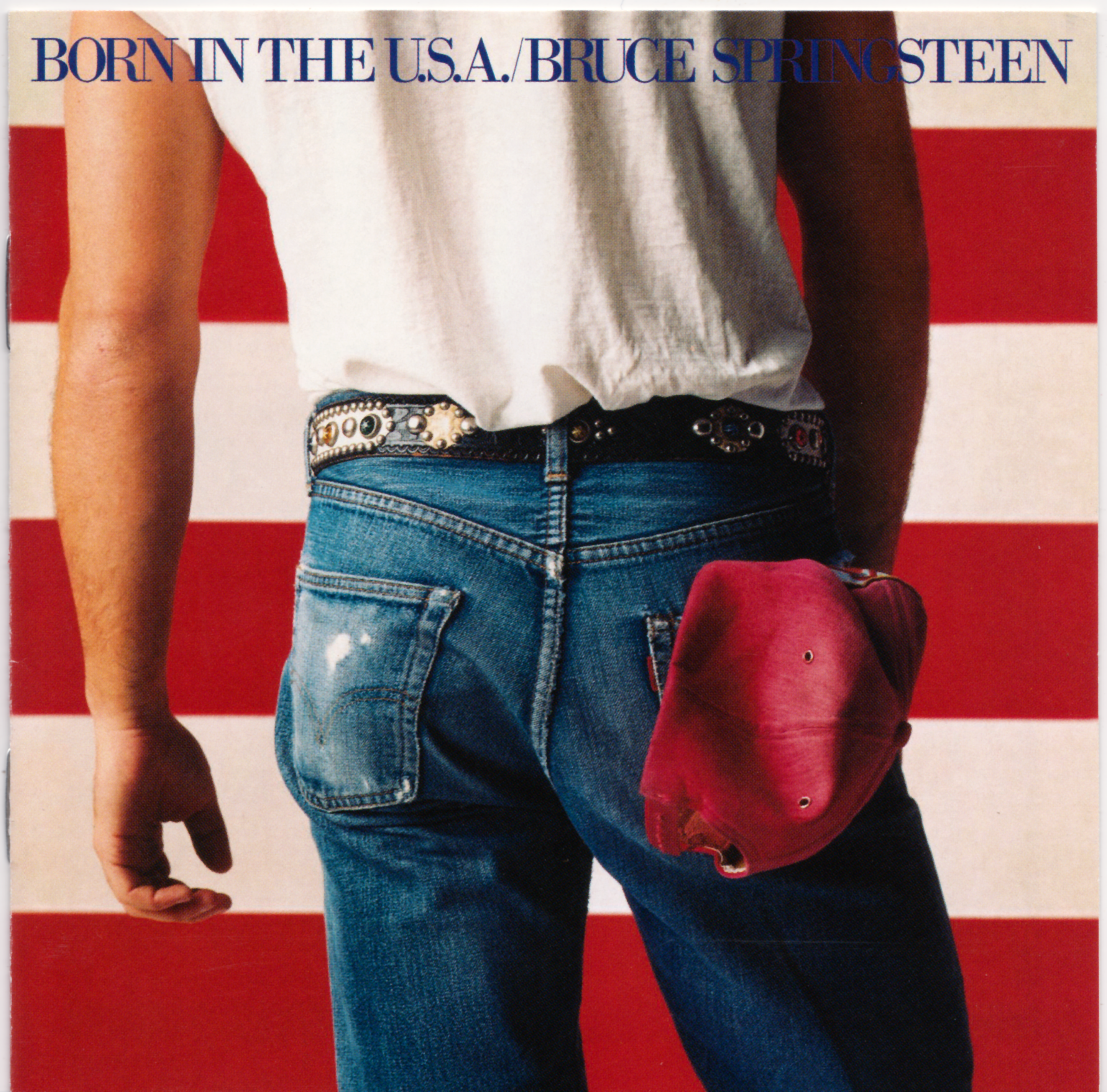 A person in jeans and a white t-shirt stands in front of a U.S. flag, holding a red baseball cap. The text at the top reads "BORN IN THE U.S.A./BRUCE SPRINGSTEEN.