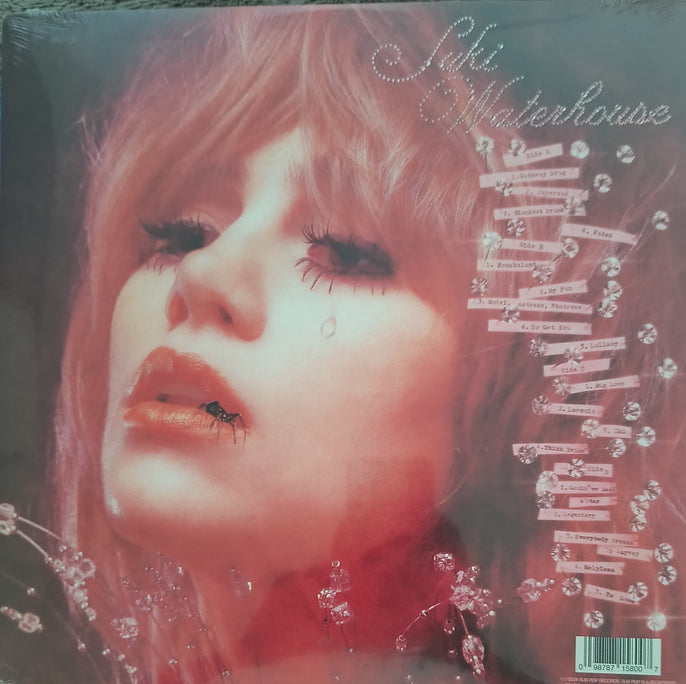 Close-up of a woman's face on a vinyl record cover, pink tones, teardrop, decorative crystals