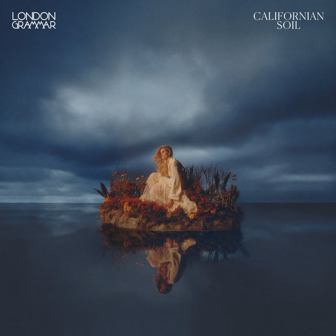 London Grammar Californian Soil album cover with woman in white dress on floral island, dramatic sky