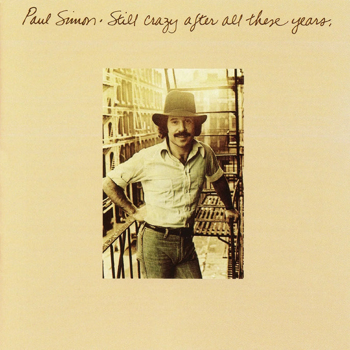 Paul Simon Still Crazy After All These Years vinyl album cover with artist in hat on fire escape