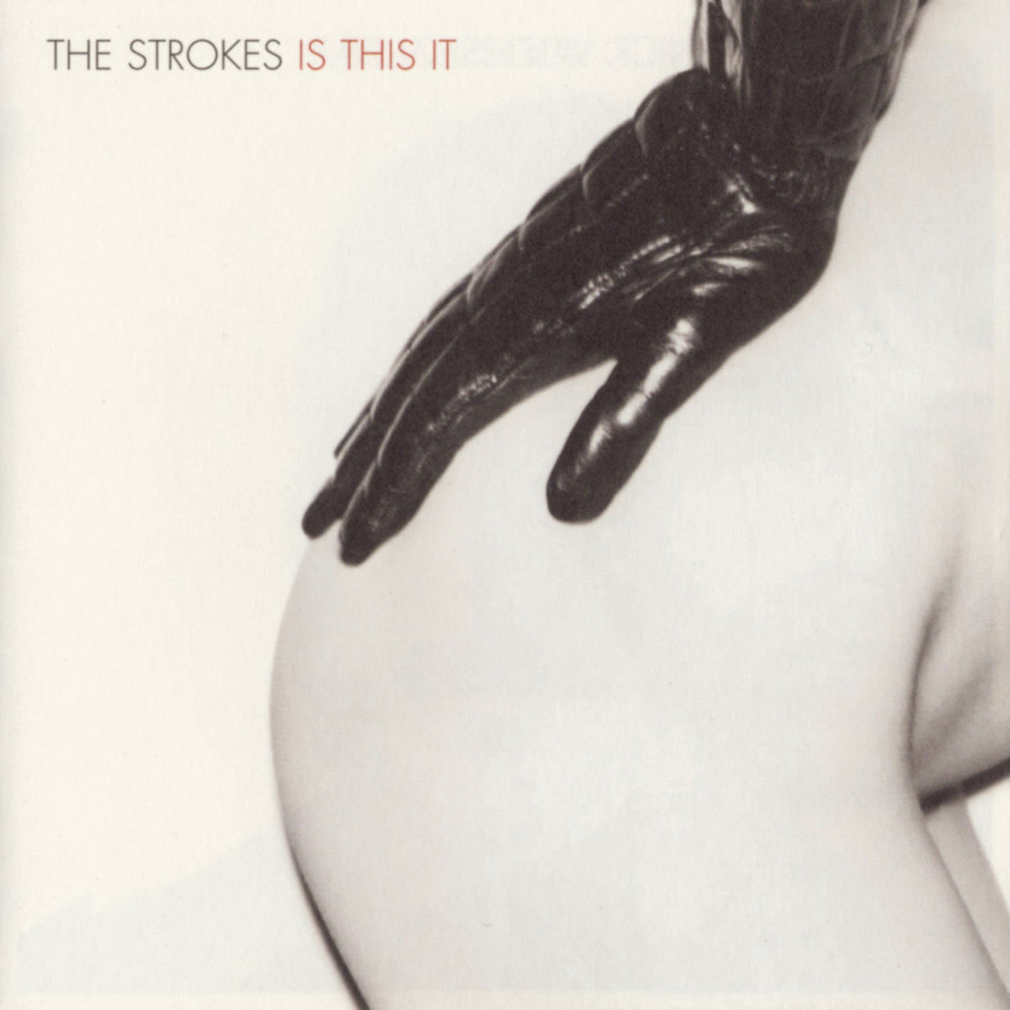 A gloved hand rests on a bare hip against a plain background; album title "The Strokes Is This It" appears in the top left corner.