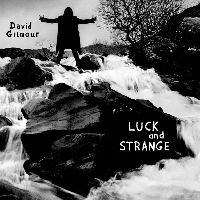 Black and white album cover with a person standing on rocks by a waterfall, text reads 'Luck and Strange'.