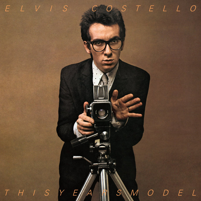 Vinyl album cover showing a man in a suit with glasses posing behind a vintage camera.