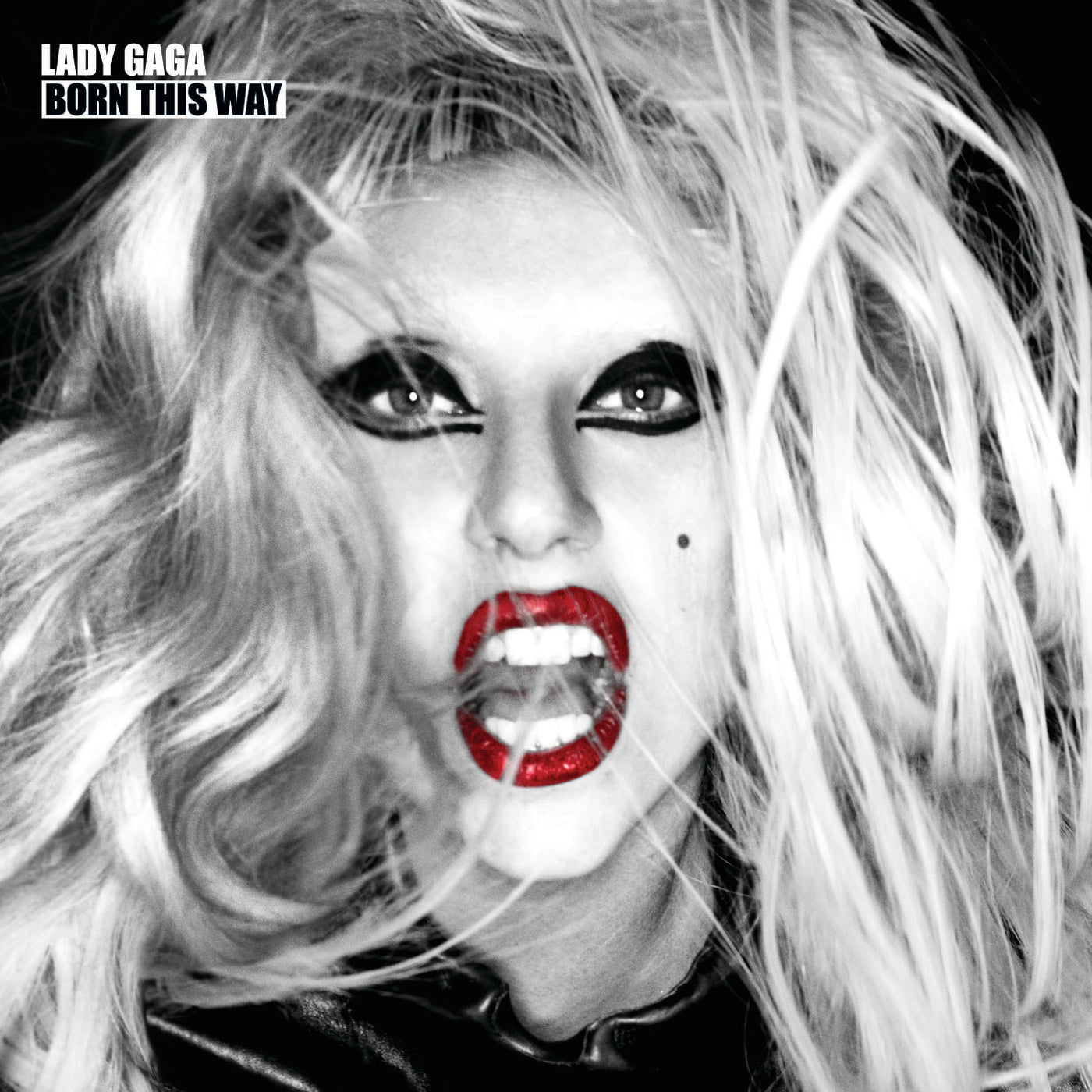 Black and white close-up of a person with wild blond hair, bold eye makeup, bright red lipstick, and an open mouth, with "LADY GAGA BORN THIS WAY" text in the top left corner.