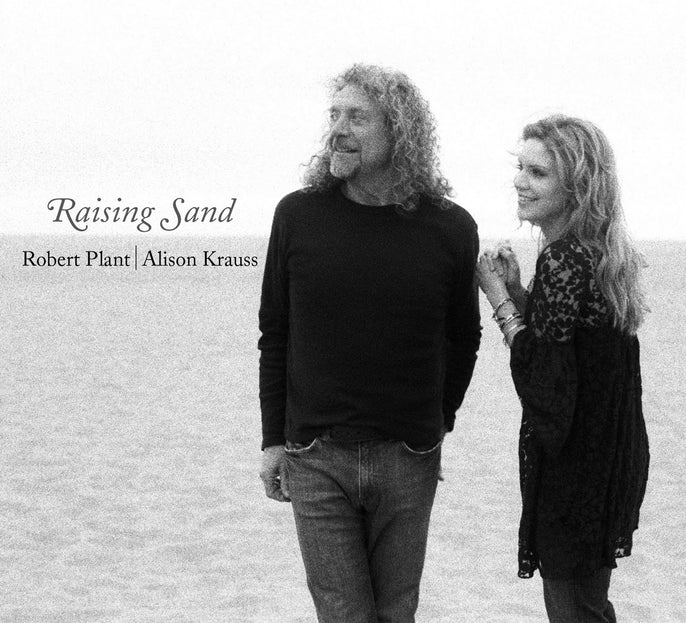 Raising Sand album cover featuring two people smiling on a beach in black and white.