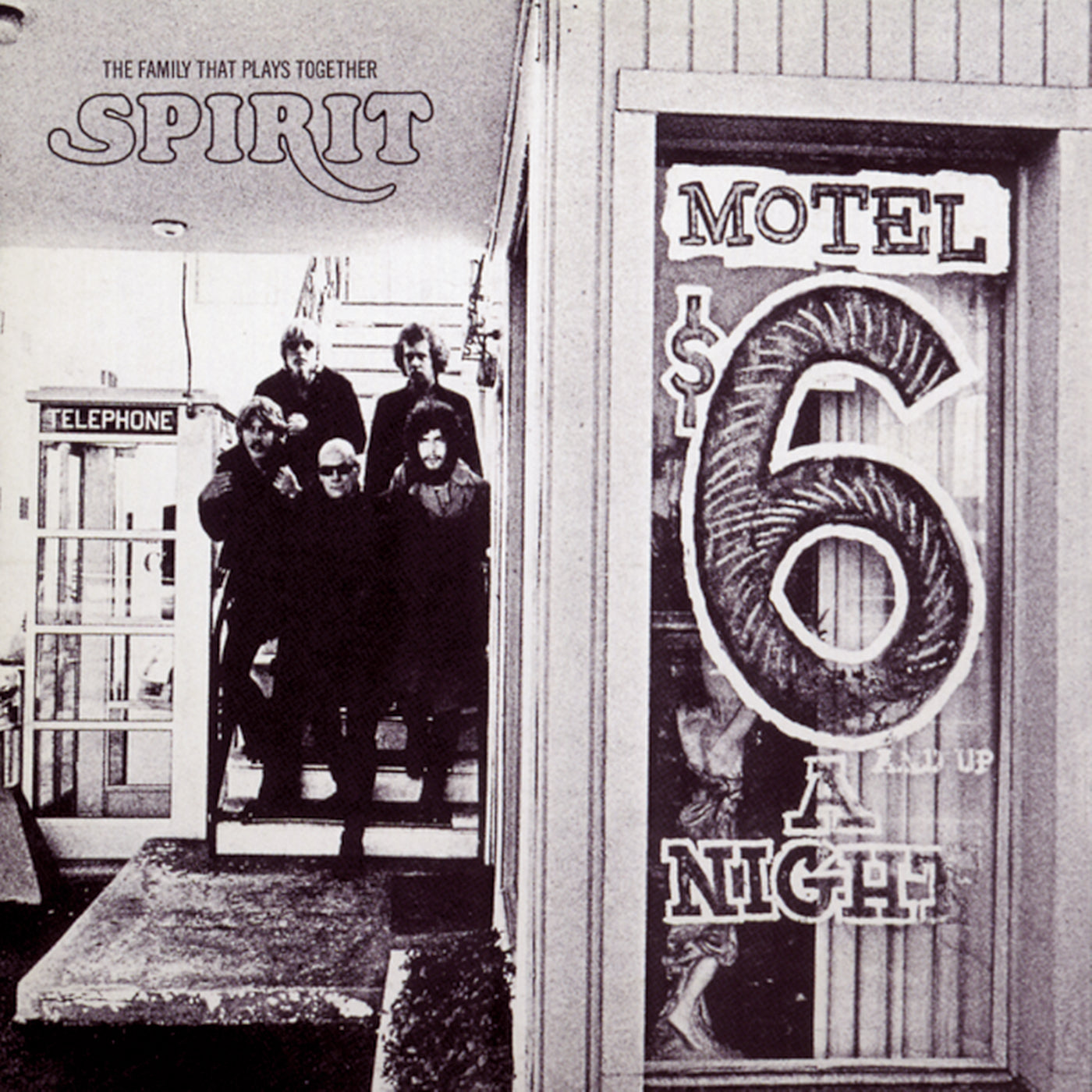 A band poses on stairs beside a motel office window displaying a large “$6 a night” sign; a phone booth is visible in the background.