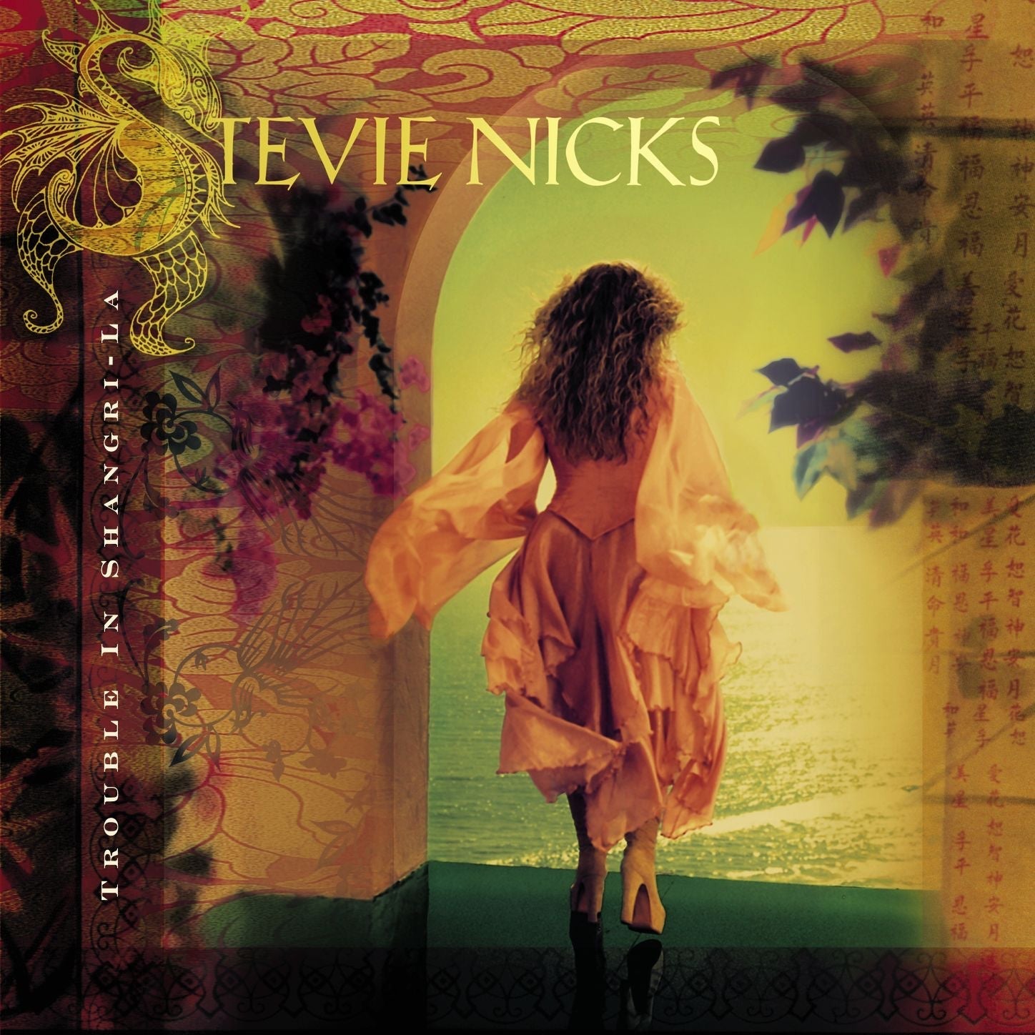 The album cover for "Trouble in Shangri-La" by Stevie Nicks features a woman in a flowing dress walking through an open archway toward a bright, sunlit landscape.