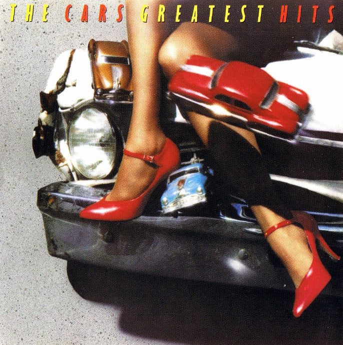 Album cover for "The Cars Greatest Hits" showing a person's legs in red high heels resting on a vintage car’s bumper, with a toy car nearby.