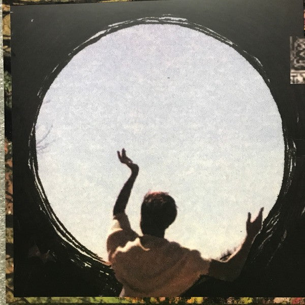 Silhouette of person raising arms in front of large circular window, vinyl album cover art.