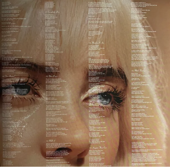 Close-up of woman's blue eyes with blond hair overlaid with song lyrics, vinyl record insert.