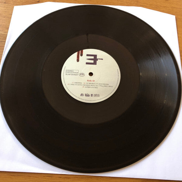 Black vinyl record album on white sleeve, featuring labeled center with tracklist and Side D marking