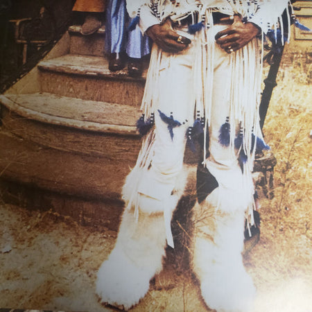 Person wearing white fringed pants and furry boots on rustic outdoor steps, vintage style