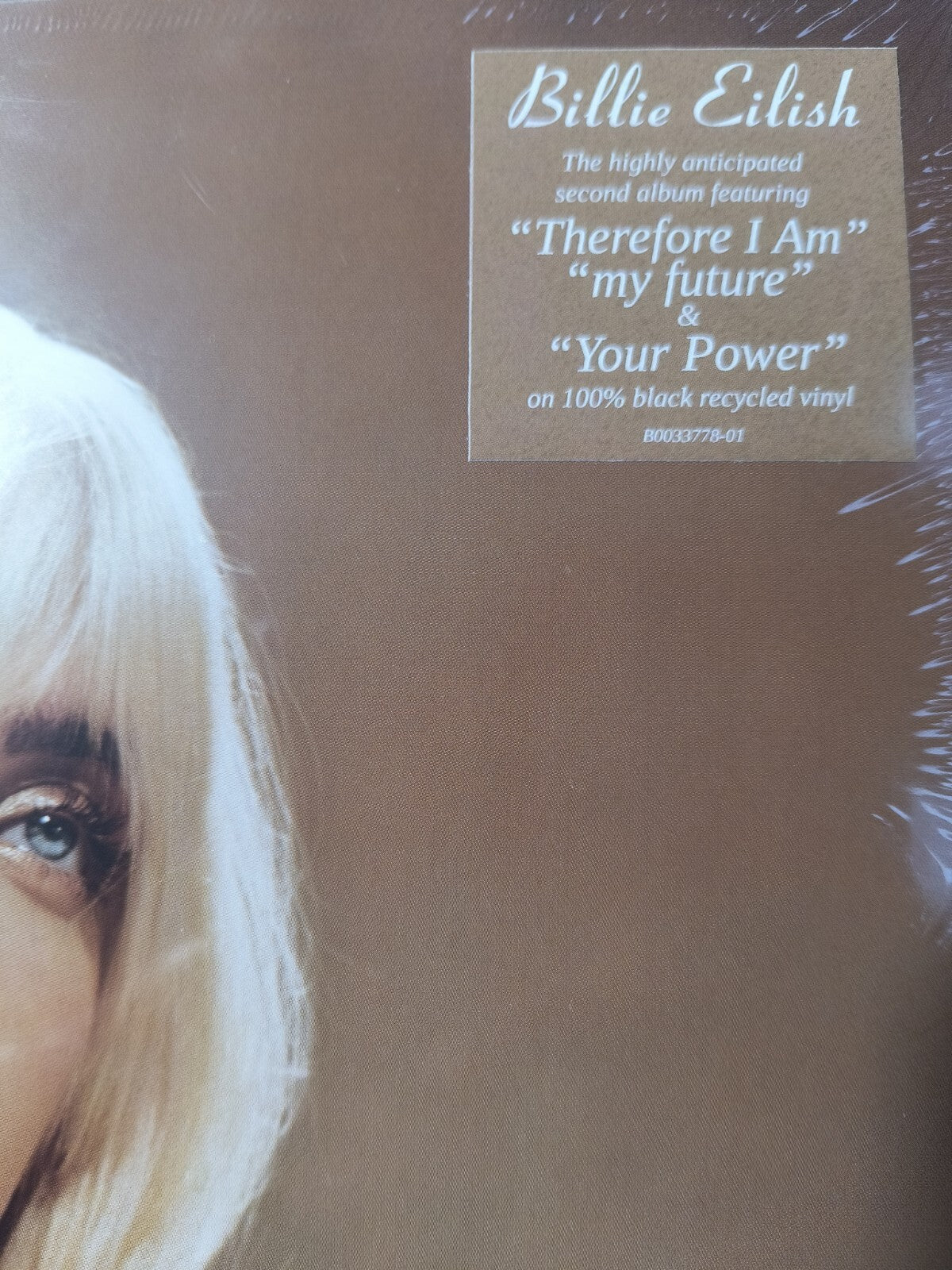 Close-up of a blonde woman’s face next to a vinyl record sticker featuring popular tracks.