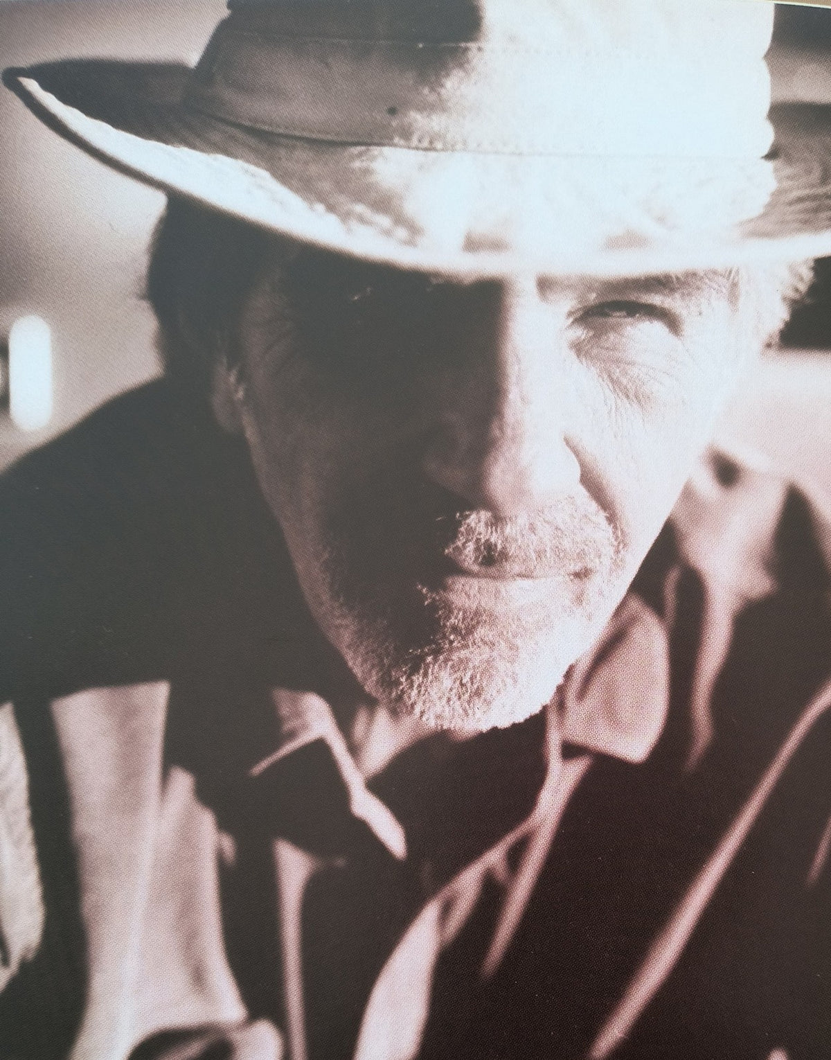 Close-up sepia portrait of an older man in a hat, dramatic lighting, vintage style