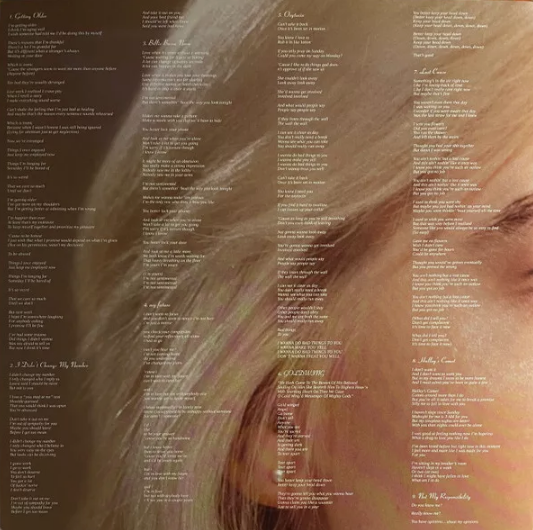 Close-up of vinyl record album insert featuring song lyrics overlaid on a woman's face with light blonde hair.