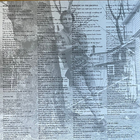 Vinyl record album insert featuring printed song lyrics over a black and white photo of a man outdoors near a tree and house.