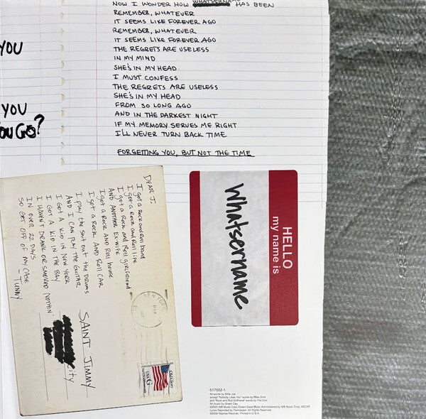 Notebook with handwritten song lyrics, postcard, and 'Hello my name is' sticker on textured surface