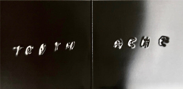 Glossy black vinyl record cover with embossed text reading 'TOOTH ACHE'.