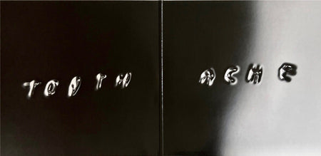Glossy black vinyl record cover with embossed text reading 'TOOTH ACHE'.