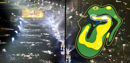 Large outdoor concert crowd at night with colorful abstract tongue and lips vinyl album art