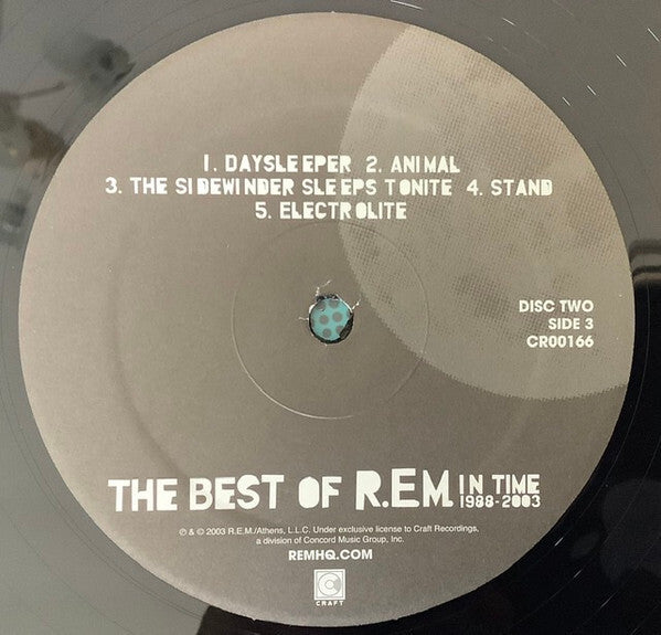 Close-up of The Best of R.E.M. In Time 1988-2003 vinyl record label, disc two, side 3, tracklist visible.