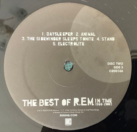 Close-up of The Best of R.E.M. In Time 1988-2003 vinyl record label, disc two, side 3, tracklist visible.