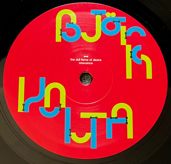 Red vinyl record label with bold yellow and blue text, track titles visible at center