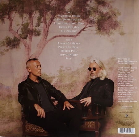 Two men in black jackets seated against a painted tree backdrop, vinyl album tracklist visible.