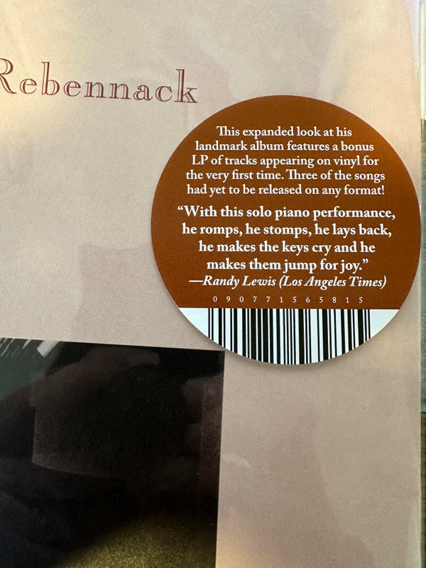 Vinyl album cover with brown sticker highlighting bonus LP, unreleased tracks, and solo piano performance review.