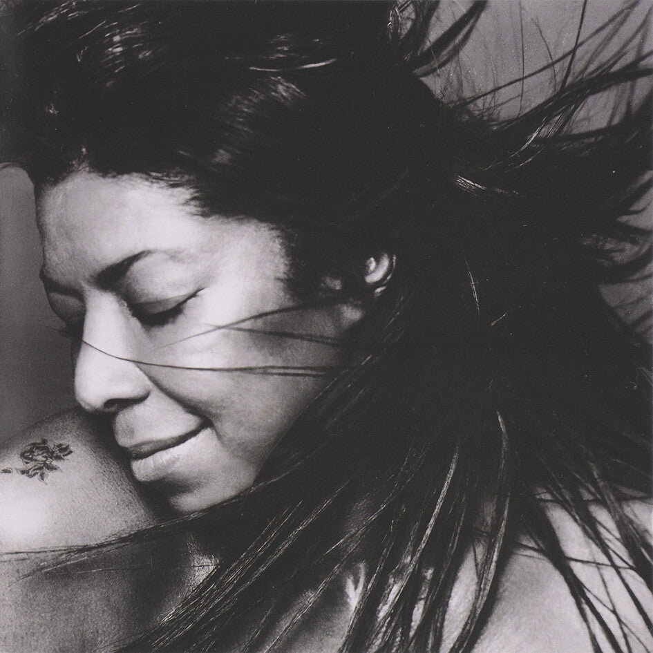 Black and white close-up of woman with flowing hair and shoulder tattoo, music album cover