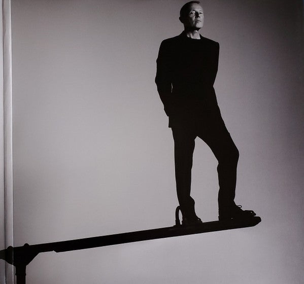 Black and white photo of a man in a suit balancing on a narrow beam, minimalistic style.