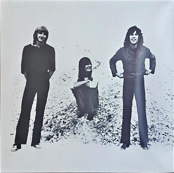 Black and white photo of three men, two standing and one sitting on gravel, classic rock vinyl cover