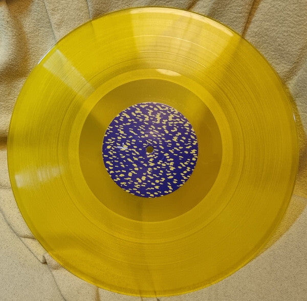 Yellow translucent vinyl record with blue and yellow speckled center label on fabric